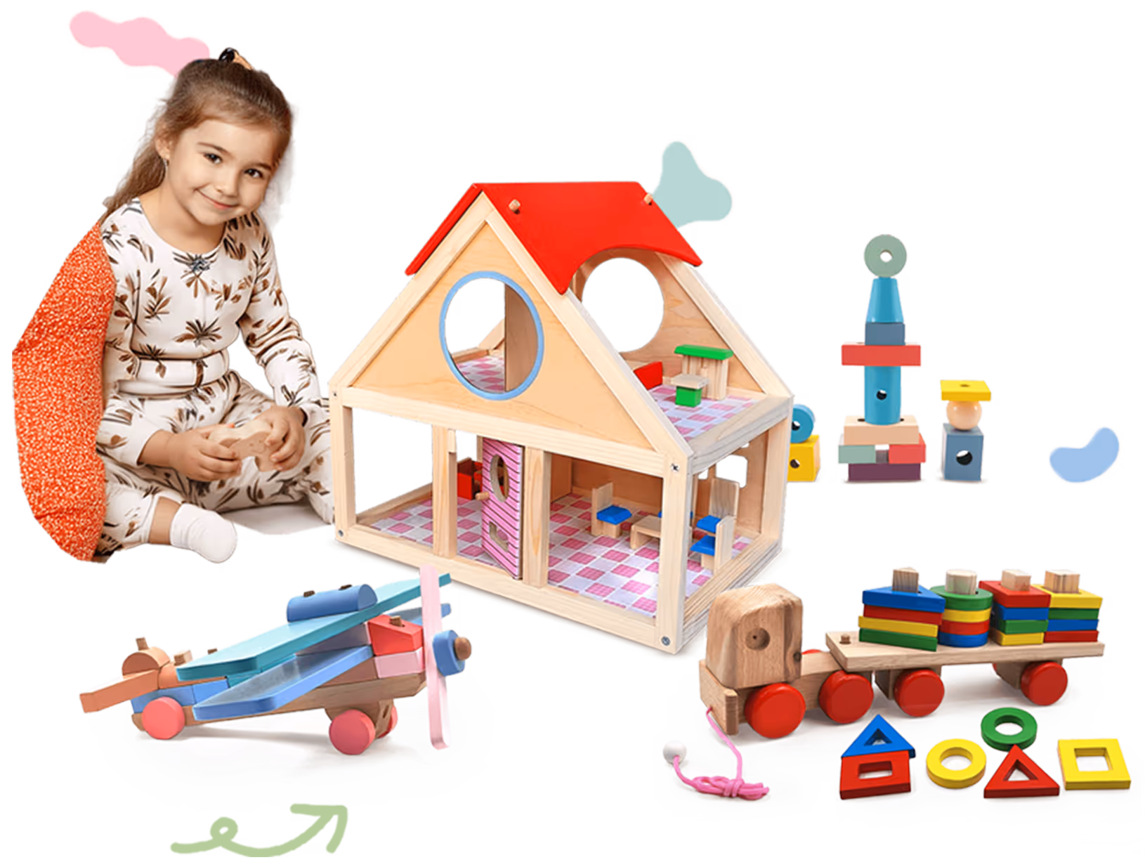 Smiling toddler girl with light brown hair sitting near wooden toys including a dollhouse, airplane, toy train, and colorful stacking blocks.